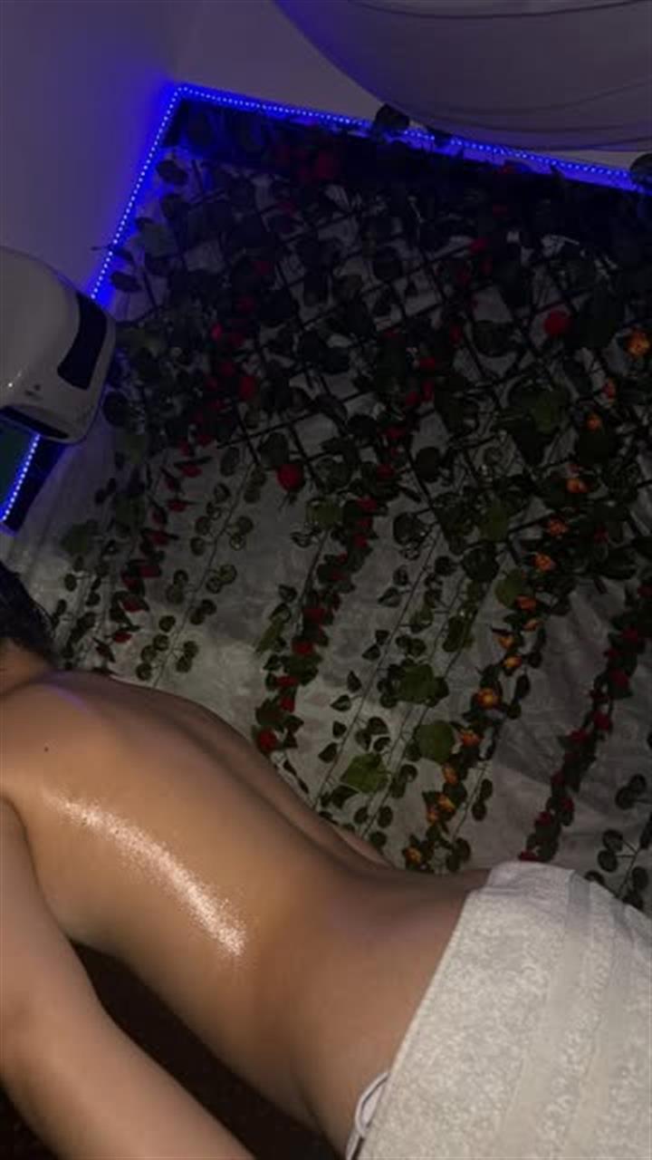 Masaje de espalda con aceite en la cabina de enredaderas iluminada